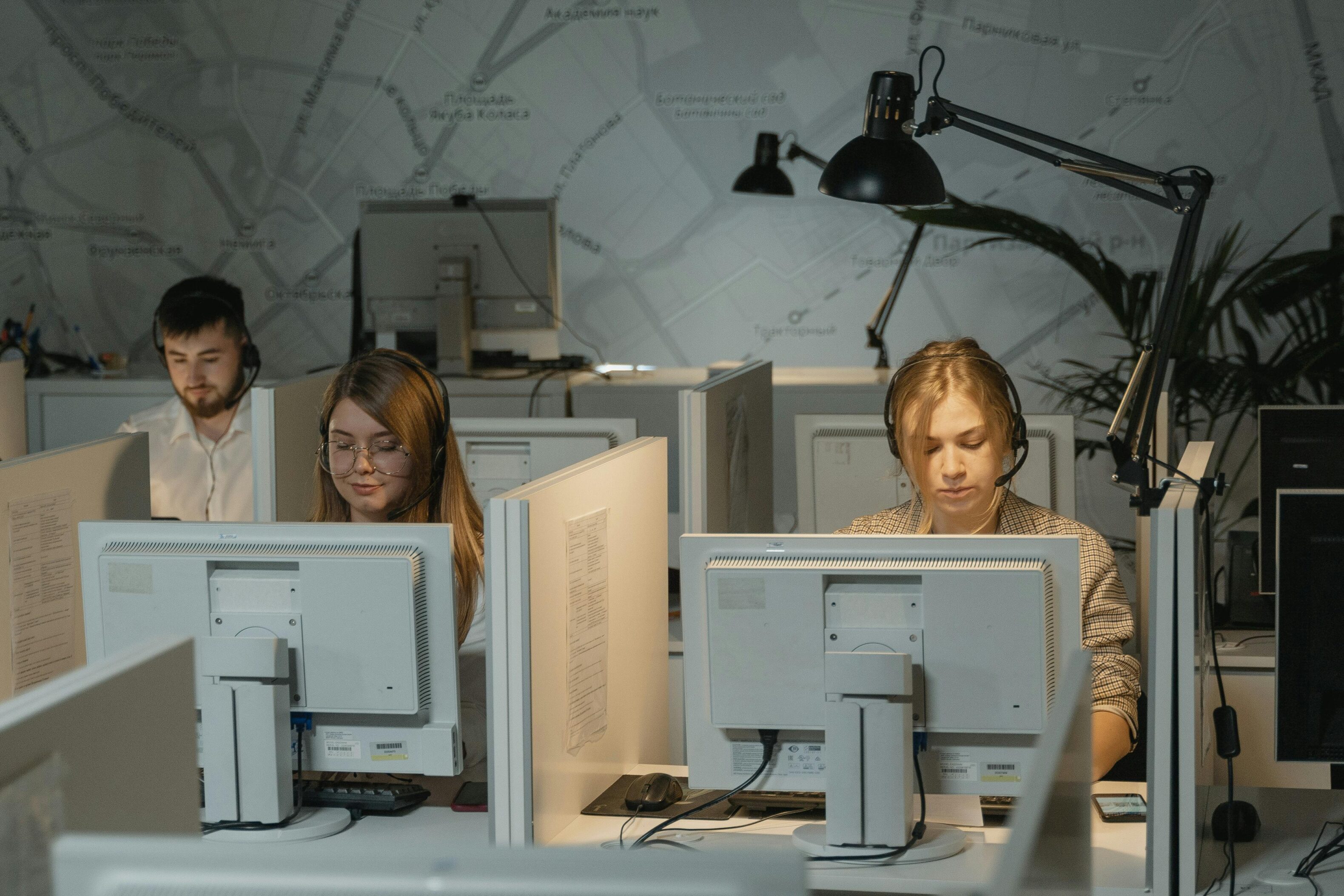 Operatori di call center B2B con cuffie e software CRM in cloud per il telemarketing, in un ambiente di lavoro moderno