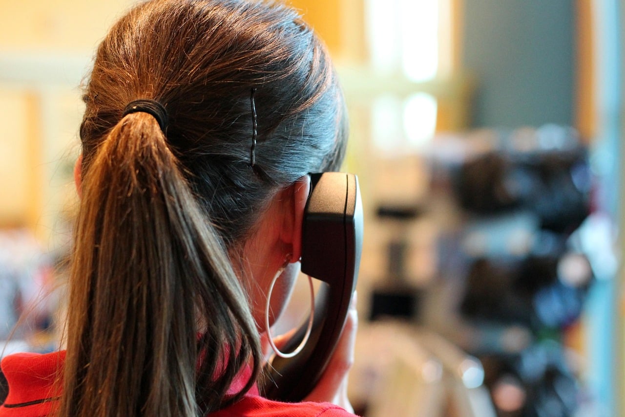 Operatrice di call center al telefono, di spalle, in un ambiente lavorativo — rappresentazione delle soft skills nella comunicazione con il cliente.