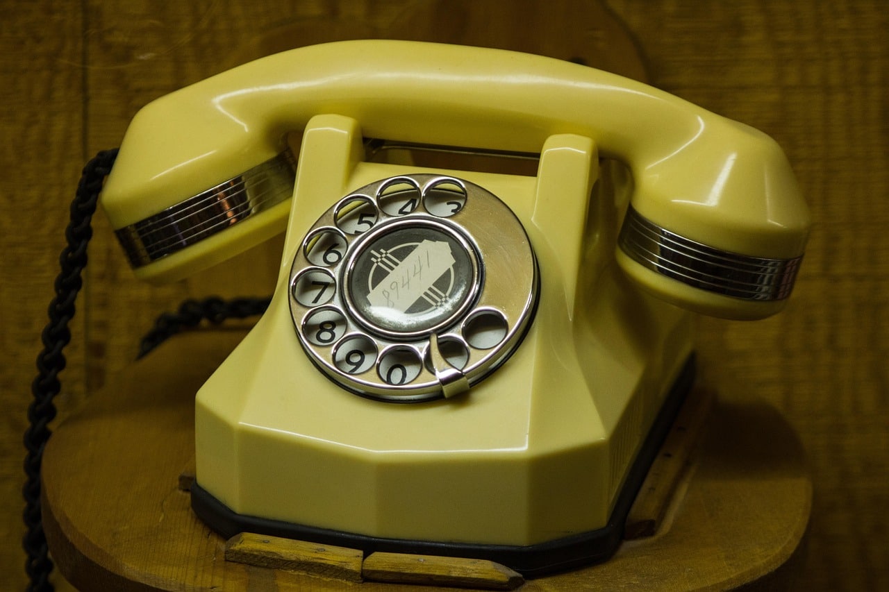 Telefono vintage a disco color crema su base in legno, simbolo del servizio clienti e dei call center inbound.